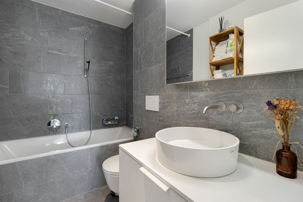 une salle de bains grise avec un lavabo, une baignoire, une douche et des toilettes blancs une salle de bains grise avec un lavabo, une baignoire, une douche et des toilettes blancs
