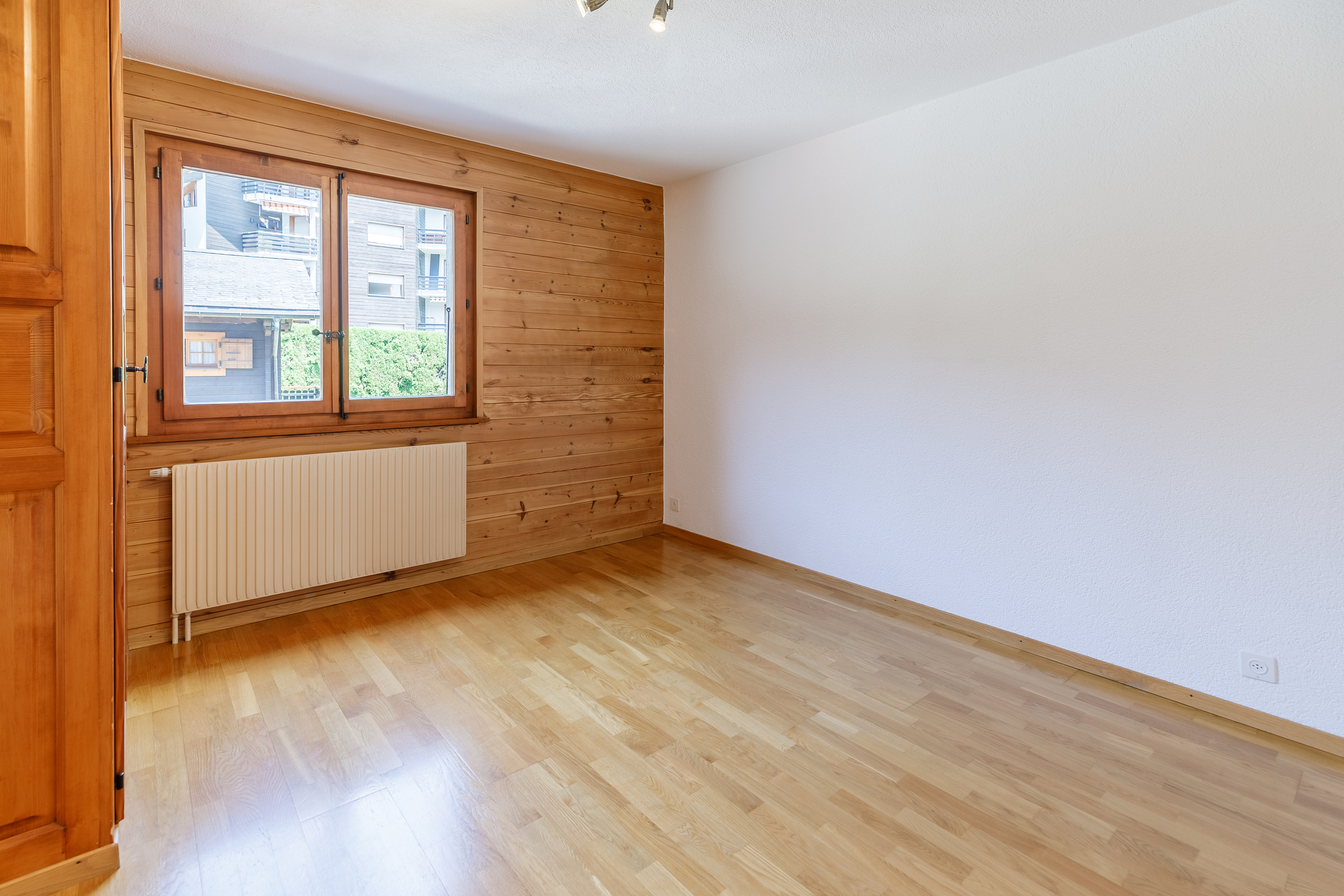 une pièce vide avec un sol en bois et une grande fenêtre