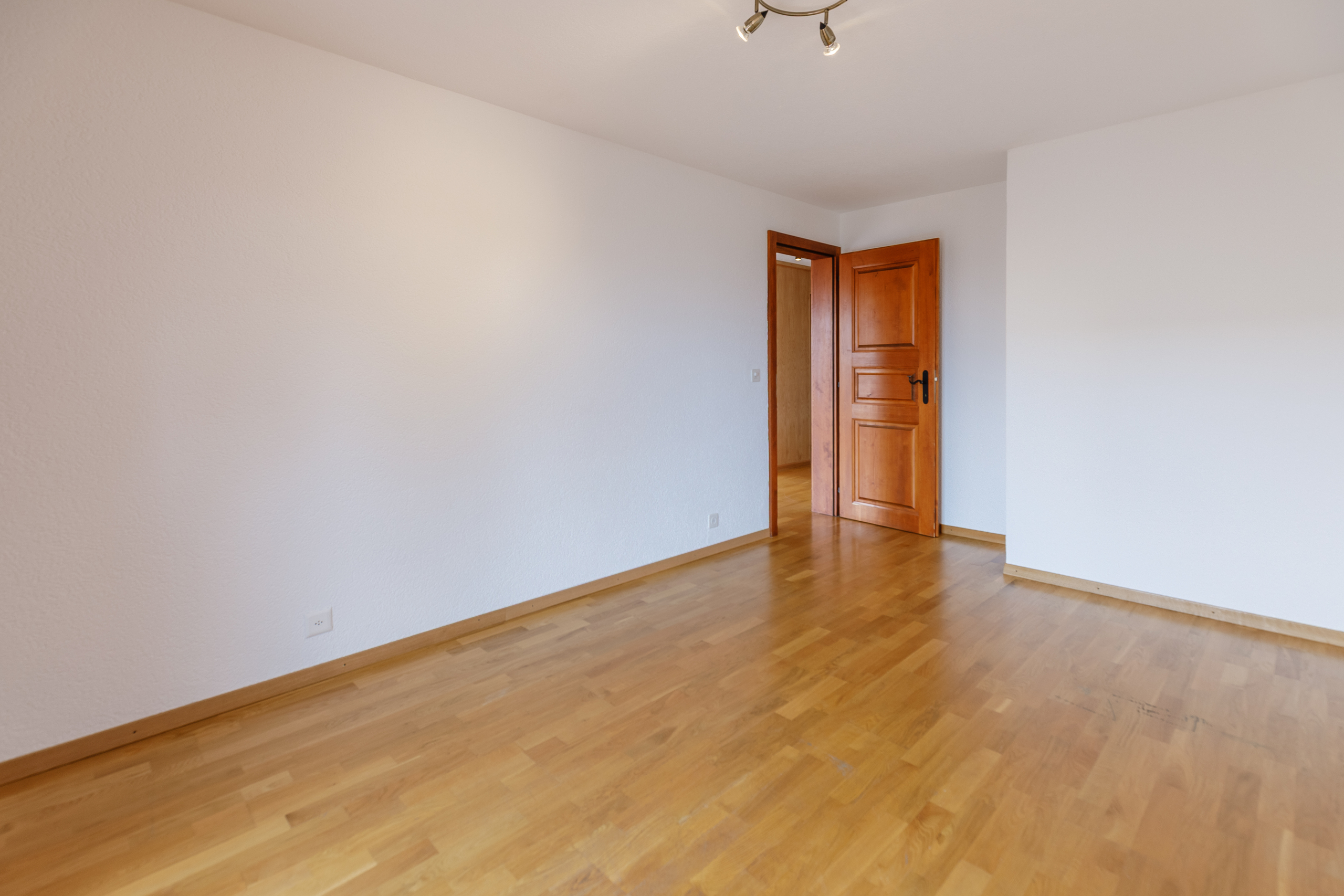 une pièce vide aux murs blancs et au sol en bois