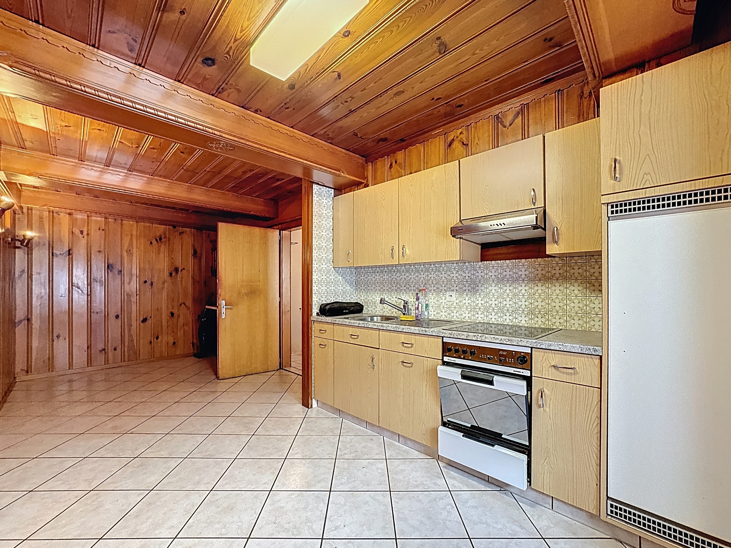 une grande cuisine avec des armoires en bois, une cuisinière et un réfrigérateur