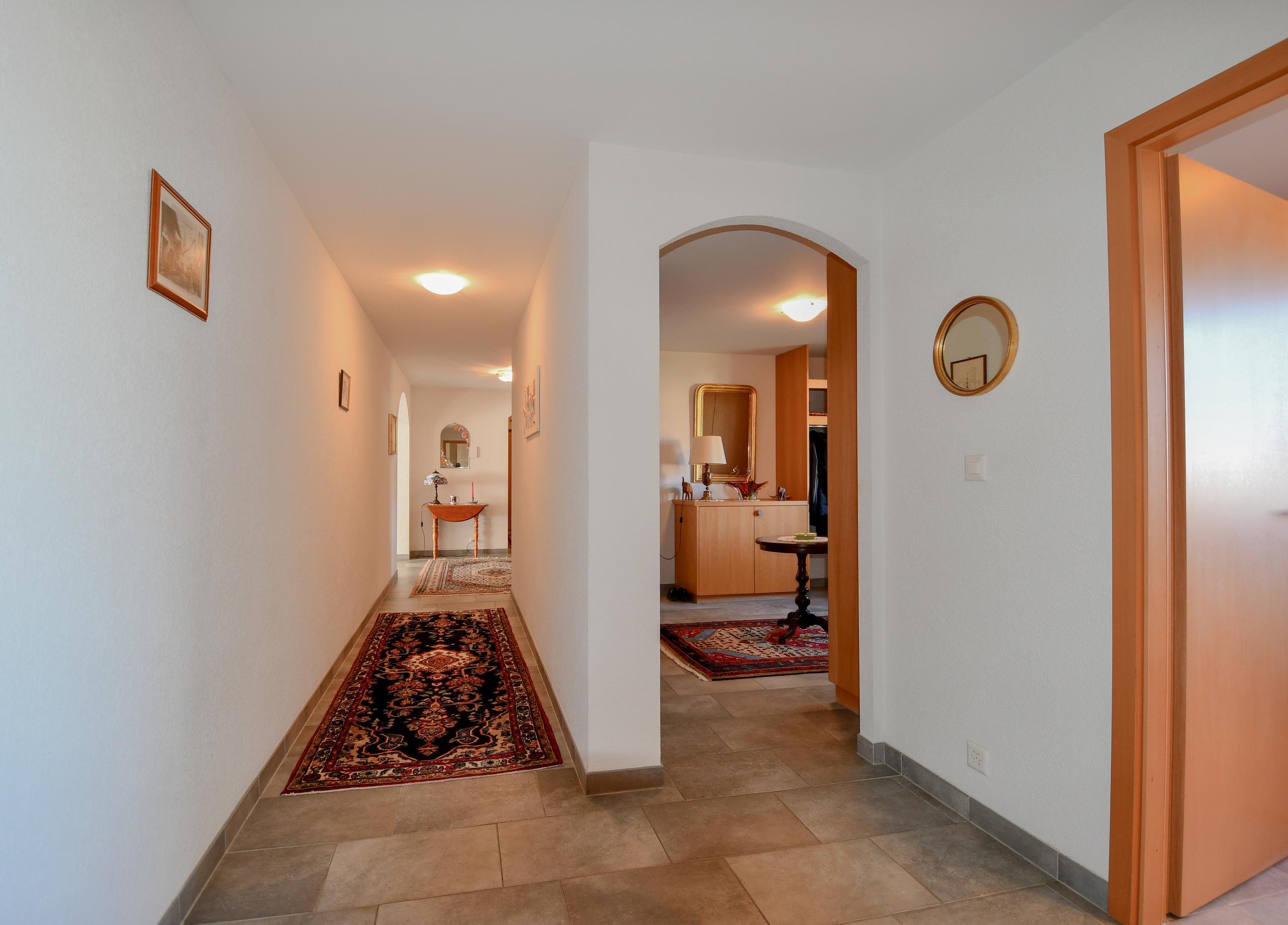 a hallway leading to a kitchen and living room with a door to another room