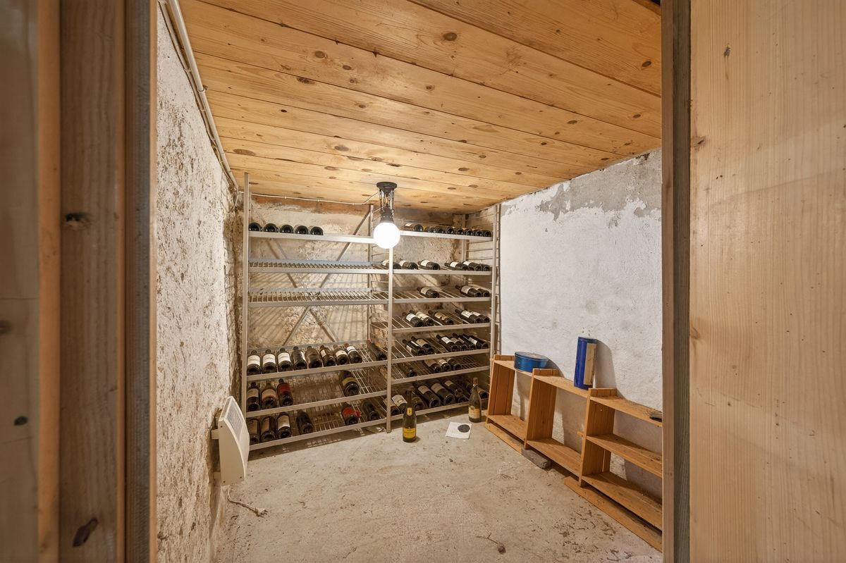 Gemütlicher Weinkeller mit hölzerner Decke und Weinregalen.