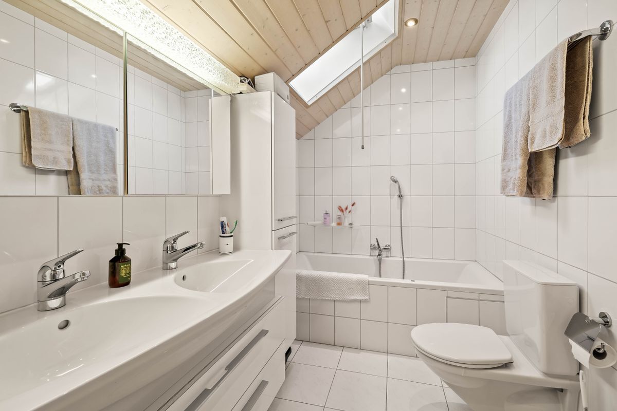 Helles Badezimmer mit Doppelwaschbecken und Badewanne.