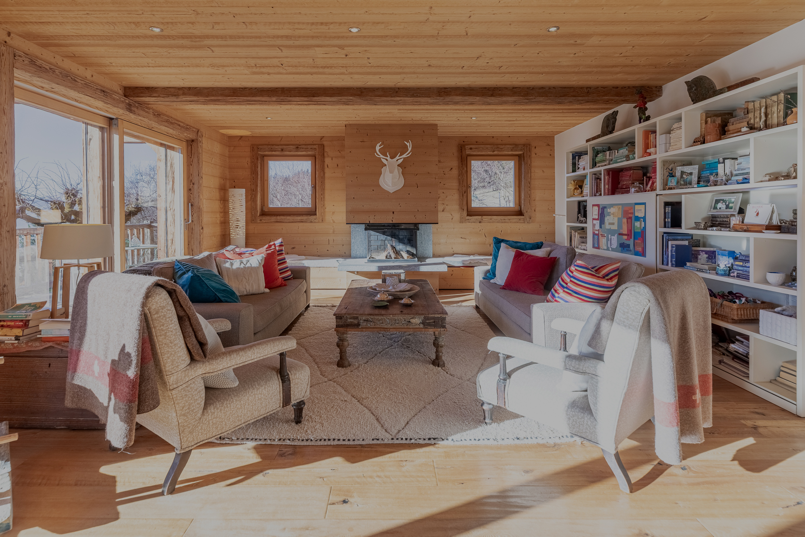 un salon avec des murs en bois, une cheminée, un canapé, des chaises et une grande bibliothèque