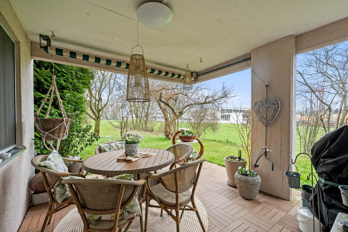 Überdachte Terrasse mit Blick auf einen grünen Garten.