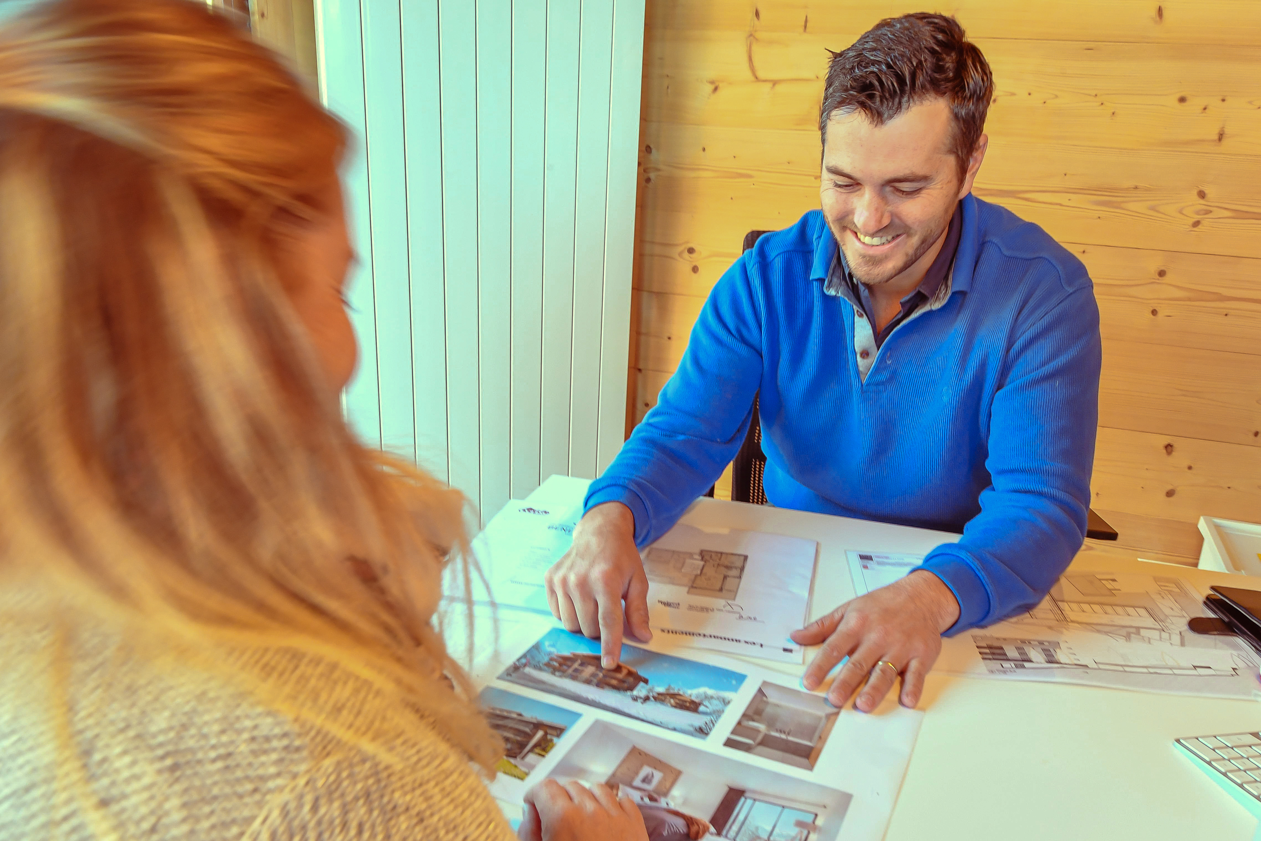 A real estate broker in discussion with a client, offering personalized advice on house plans, in a warm and friendly atmosphere.