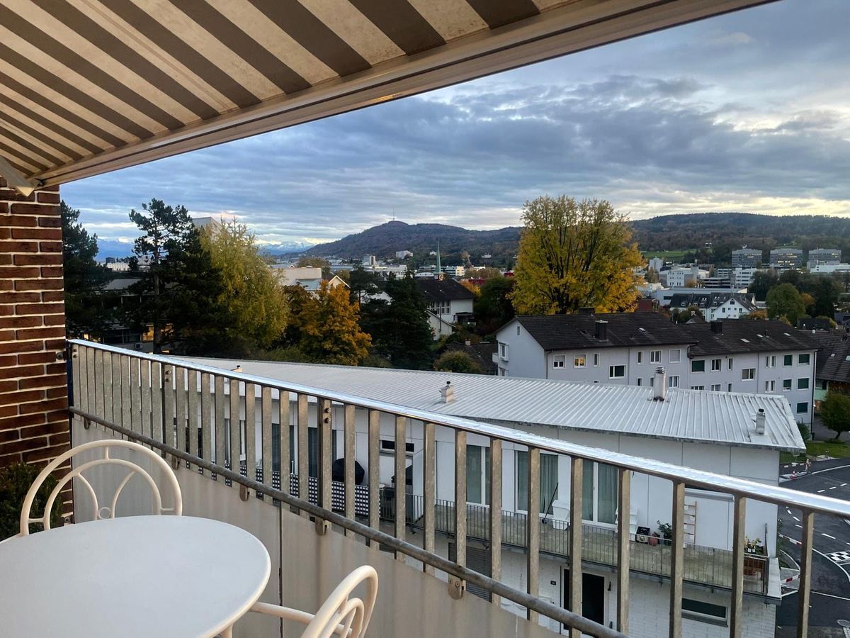 Blick auf die Stadt mit umliegenden Hügeln von einem Balkon mit Markise. Blick auf die Stadt mit umliegenden Hügeln von einem Balkon mit Markise.