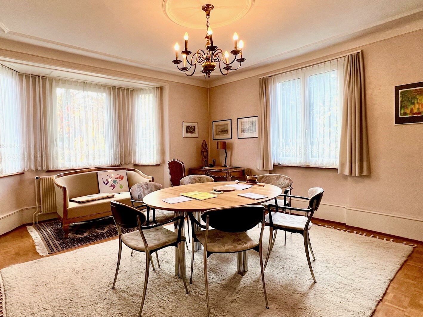 a dining table surrounded by chairs in a room with large windows
