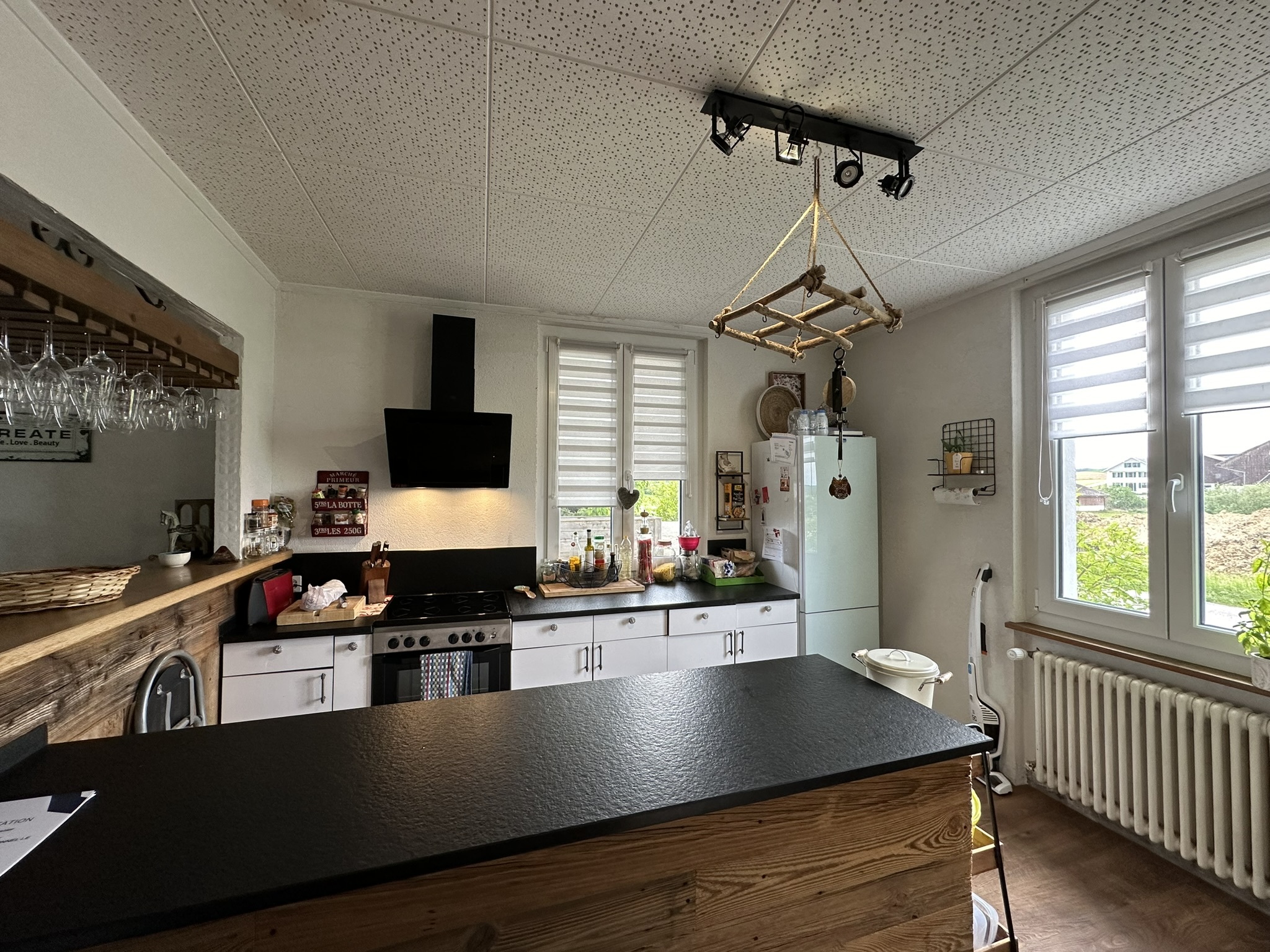 une cuisine avec une grande fenêtre et un comptoir noir au milieu de la pièce