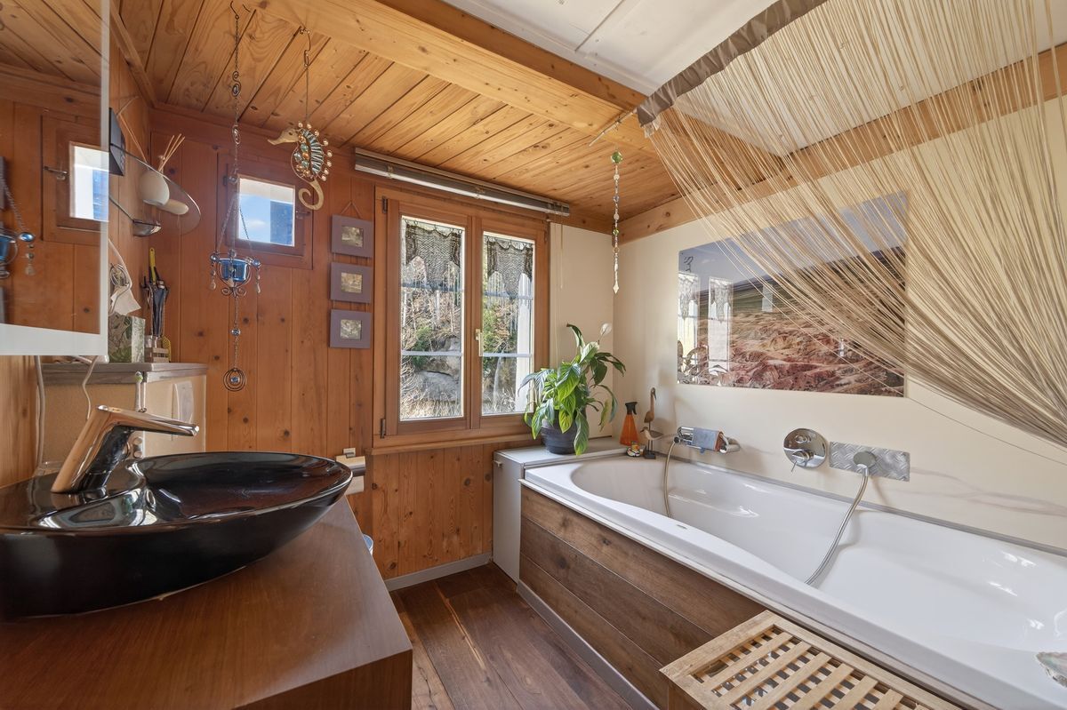 Bad mit grosser Wanne, WC und schwarzem Waschbecken.