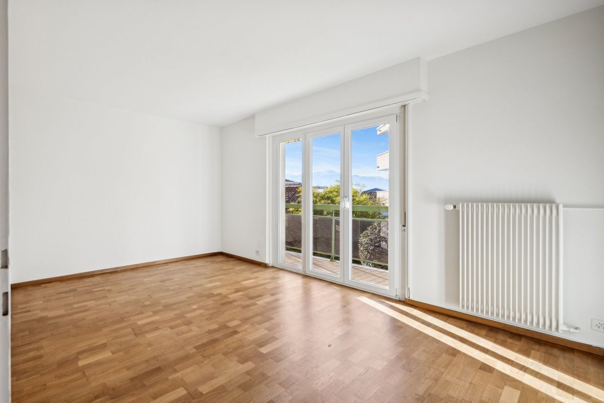 Espace lumineux avec parquet et accès au balcon.