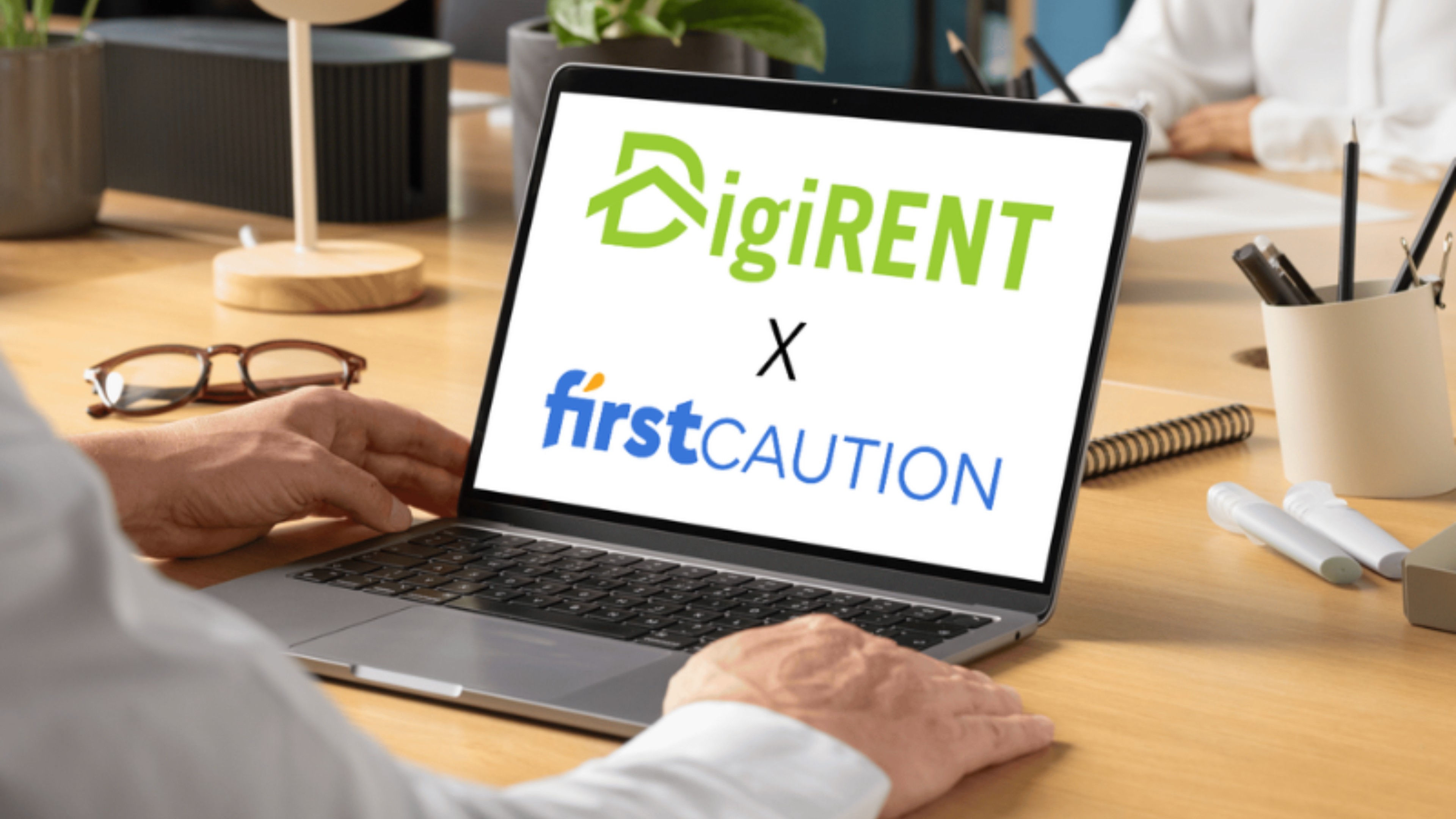 Laptop on a desk displaying the DigiRENT and Firstcaution logos, illustrating a partnership between the two companies.