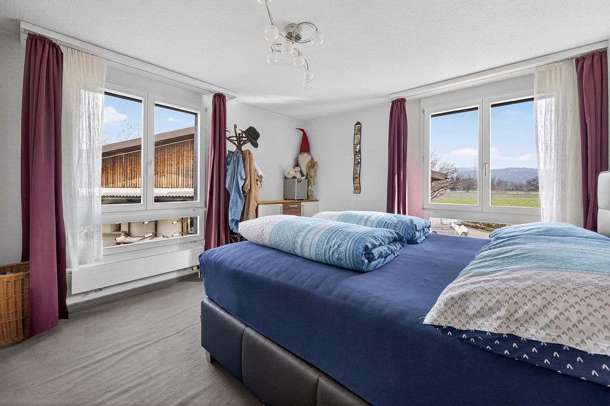 Helles Schlafzimmer mit mehreren Fenstern und Bergsicht.