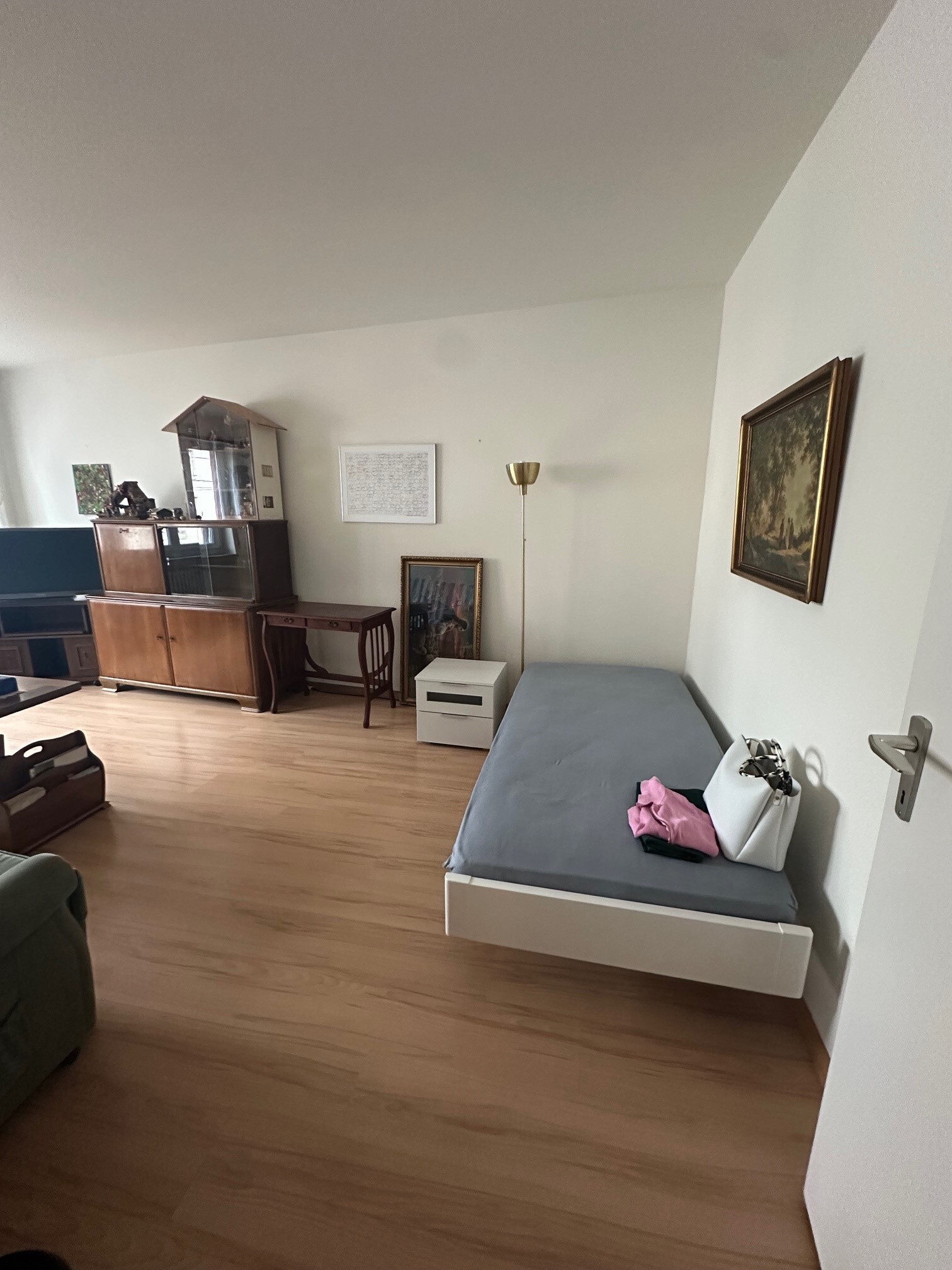 a large room with hardwood floors and a bed and couch in the middle of the room