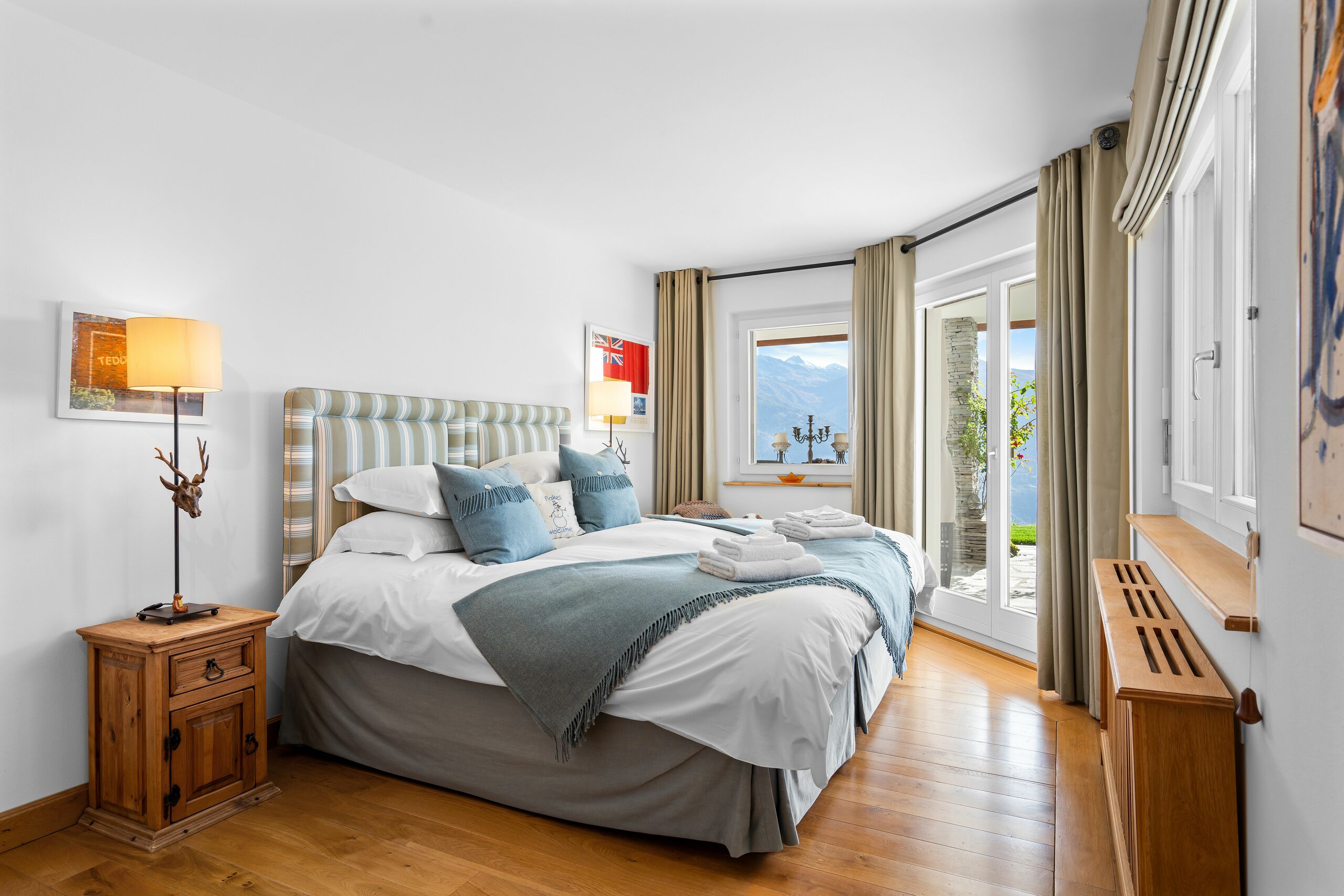 a bedroom with a double bed, a large window and a door that leads to a balcony