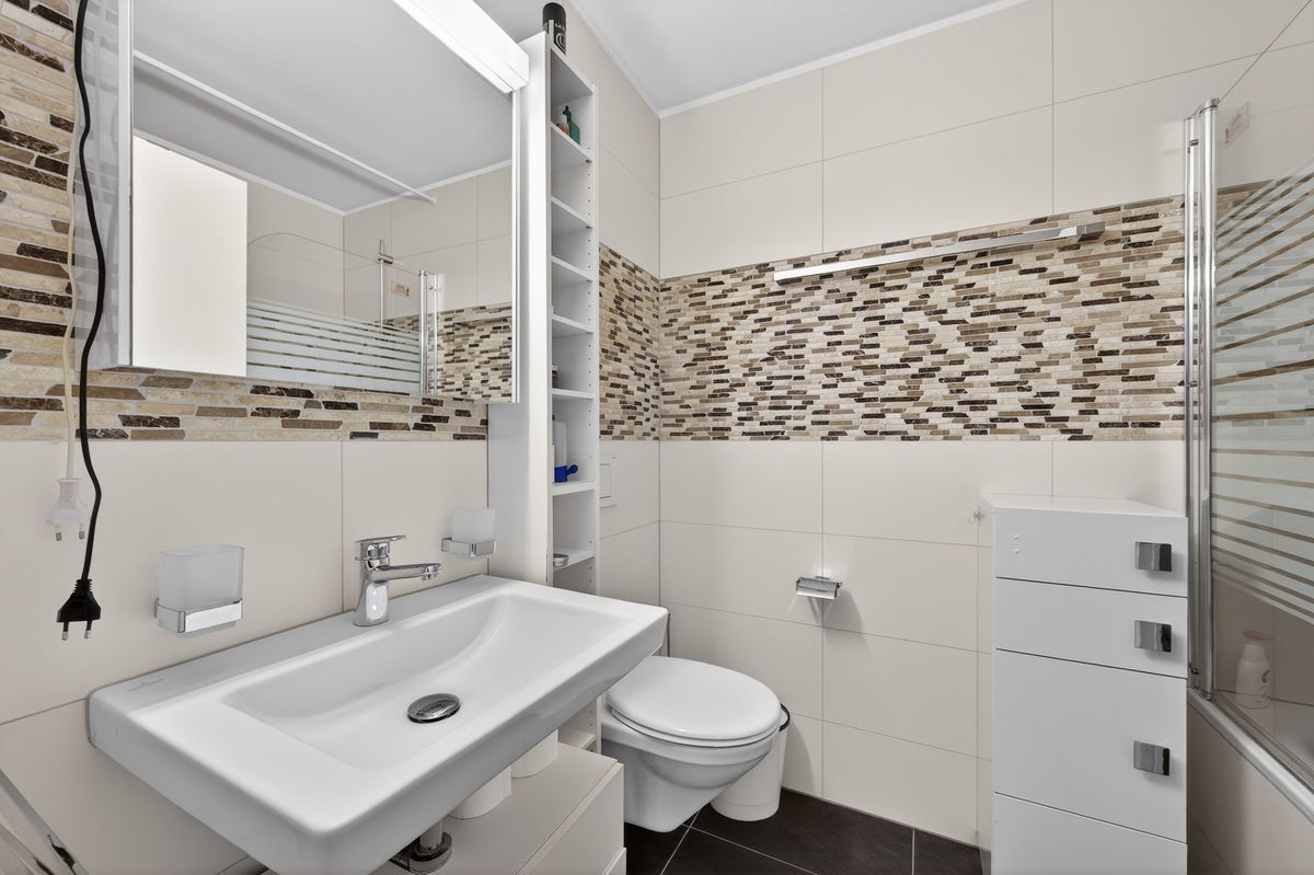 Modernes Badezimmer mit gemusterten Fliesen und Duschbadewanne.