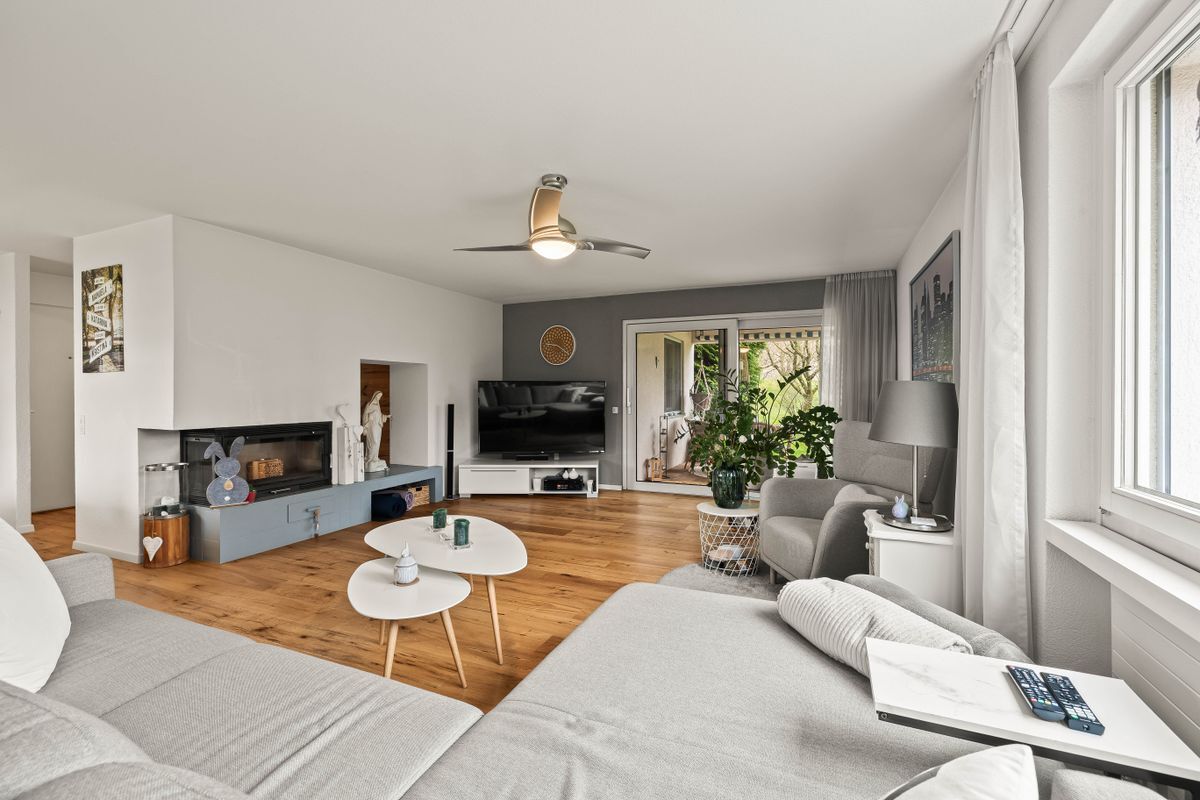 Modernes Wohnzimmer mit Fernseher und Zugang zum Balkon.